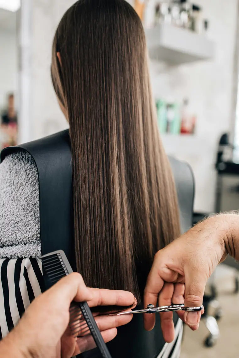 Coiffeuse réalisant une coupe de précision sur cheveux longs